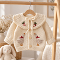 Cream knitted newborn cardigan with embroidered birds, bow collar, button front on hanger