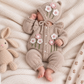 Newborn baby in beige knitted floral romper set with bonnet and booties