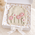 Cream knitted newborn sweater vest with pink and white flower patches on front