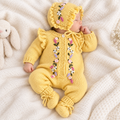 Yellow knit newborn romper with floral buttons, bonnet and tied knit booties
