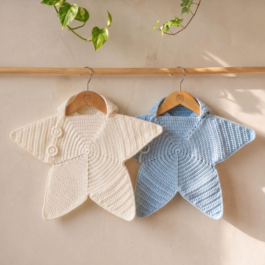 Cream and light blue crochet star baby ponchos with hood, hanging on wooden hangers
