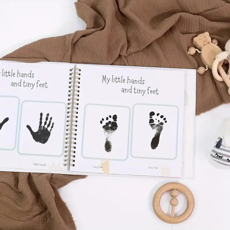 Open baby memory book page with handprint cards labeled “My little hands and tiny feet”