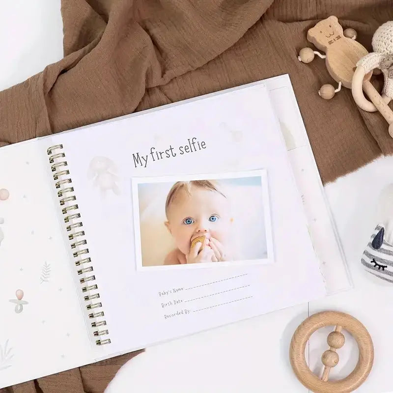 Open baby memory book page with “My first selfie” photo frame and baby footprint art
