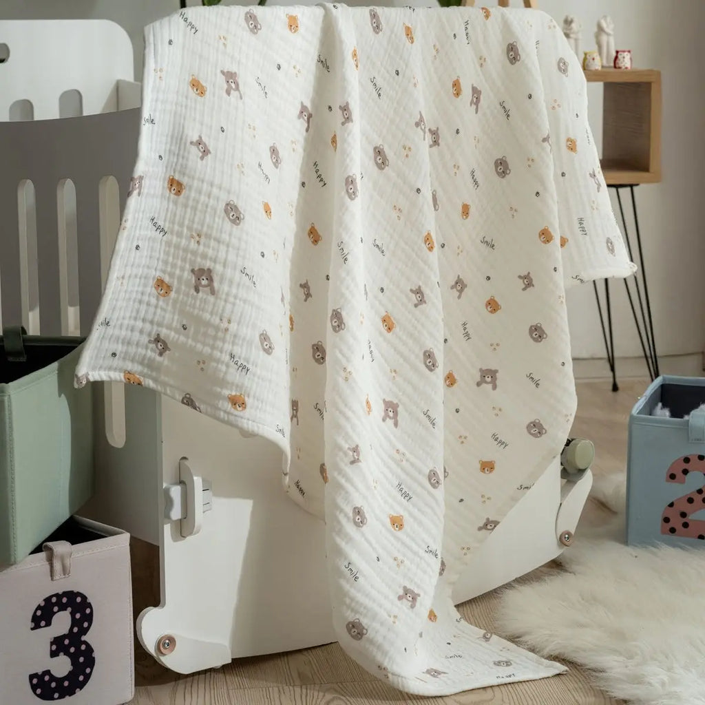 White muslin baby blanket with teddy animal print draped over a child play structure