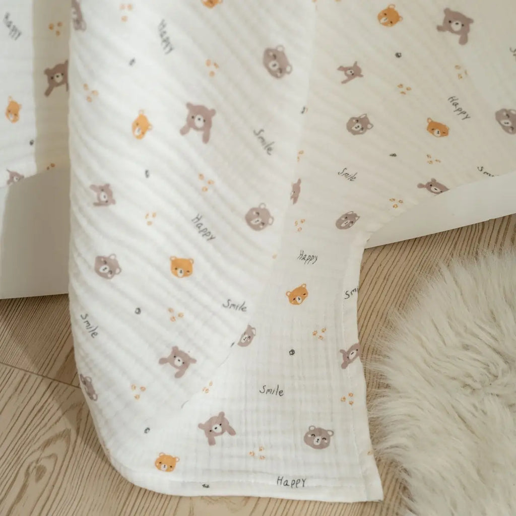 Corner of white muslin baby blanket with small teddy animal print on quilted muslin fabric