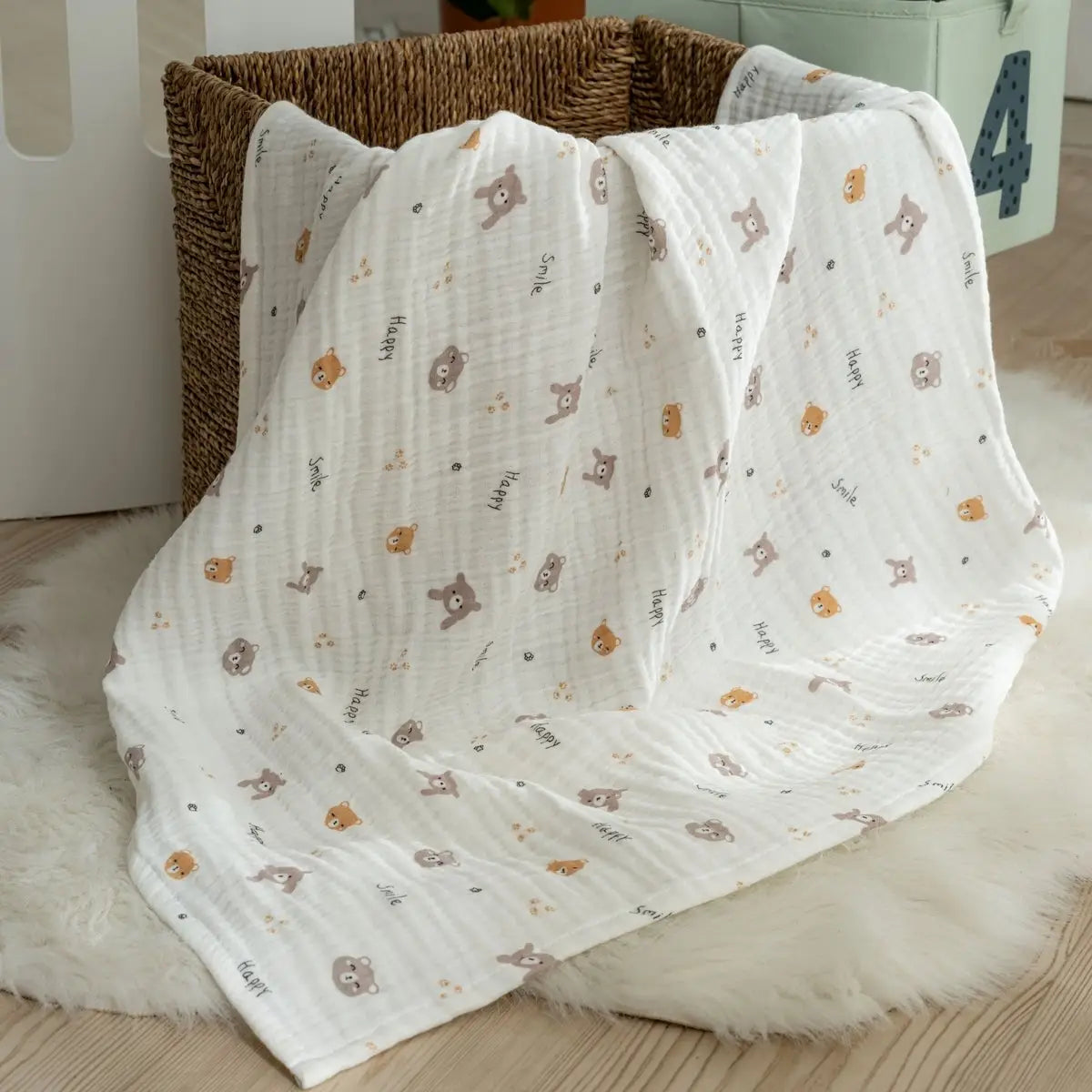 Muslin baby blanket in white with small teddy and animal pattern, soft draped fold